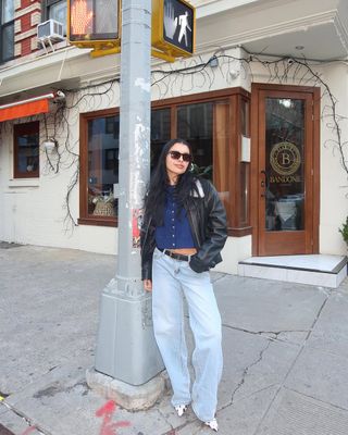 woman wearing black leather jacket and baggy jeans with stiletto heels