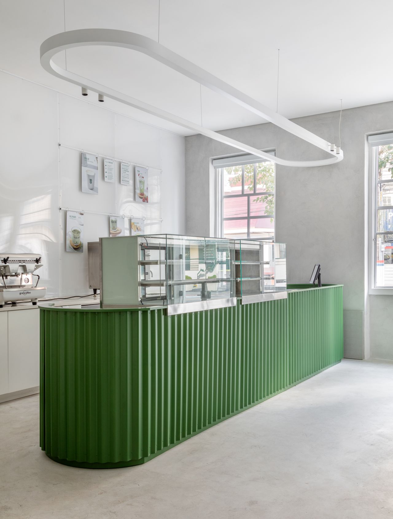 A white-washed, plastered matcha cafe with sculptural decor features monochromatic furnishings and an emerald green and chrome bar counter.
