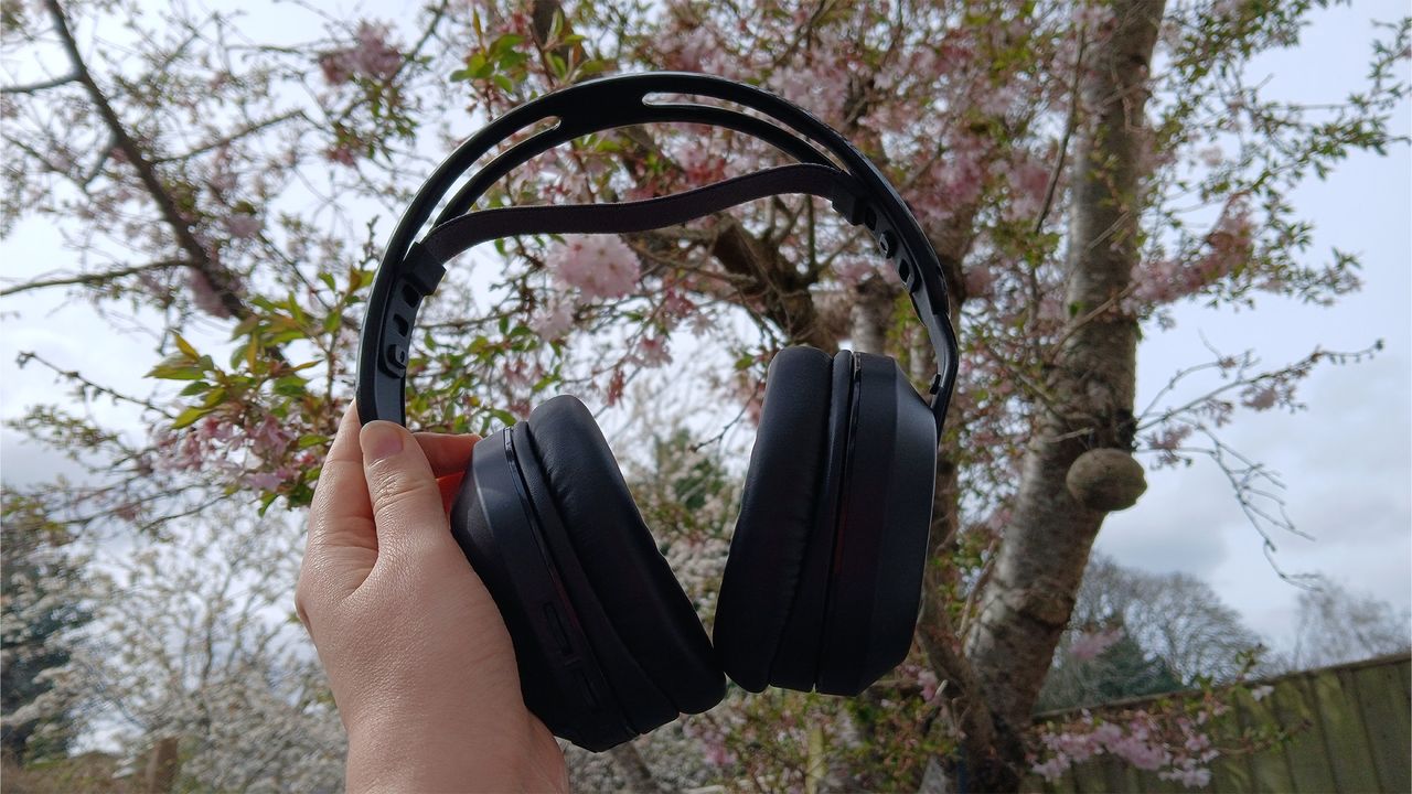 A Turtle Beach Stealth 500 headset in the black colourway, held up outdoors with a tree in the background.
