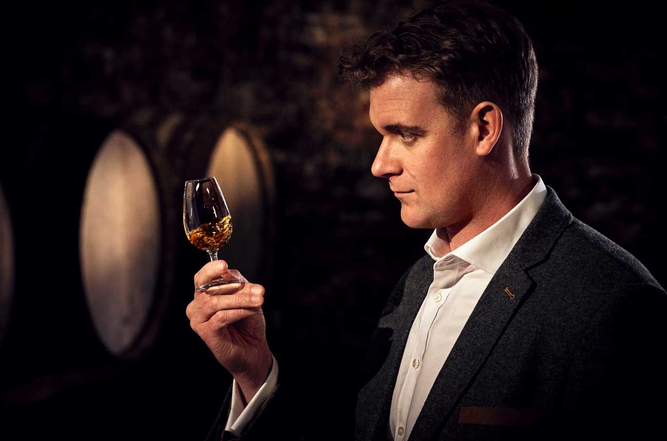 A man holds a glass of whisky to explain mizunara flavour