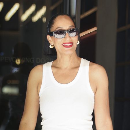 Tracee Ellis Ross wearing a white tank top, kelly green Loewe leather pants, and red Loewe pointed-toe heels