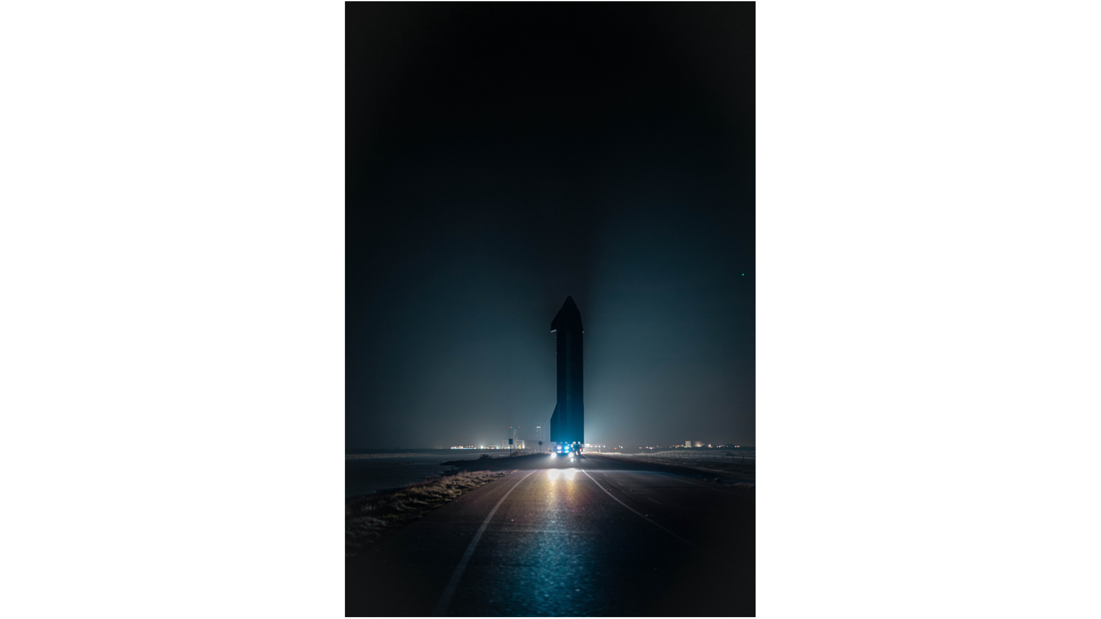 夜晚，一艘巨大的宇宙飞船在道路上行驶，背景是灯光。