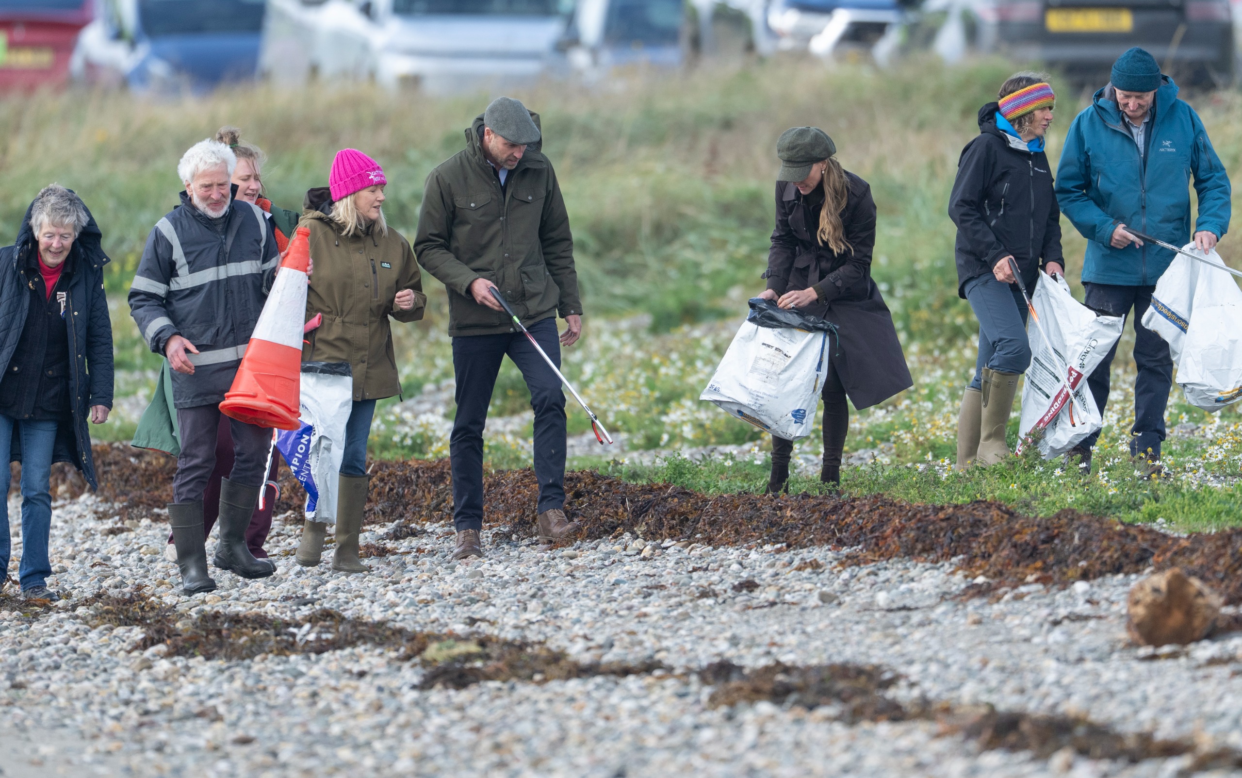 Prince William and Princess Kate cleaning trash from a beach with a group of volunteers