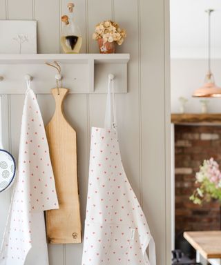 modern country kitchen in soft neutrals, featuring peg rail with hearts apron and wooden board