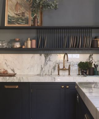 A kitchen with marble backsplash, black cabinets, and dark grey walls