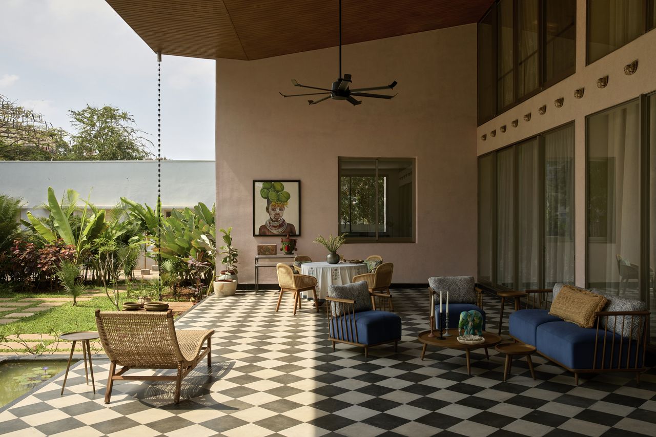 An outdoor space with chequerboard flooring, seating, a dining table with views of the tall trees
