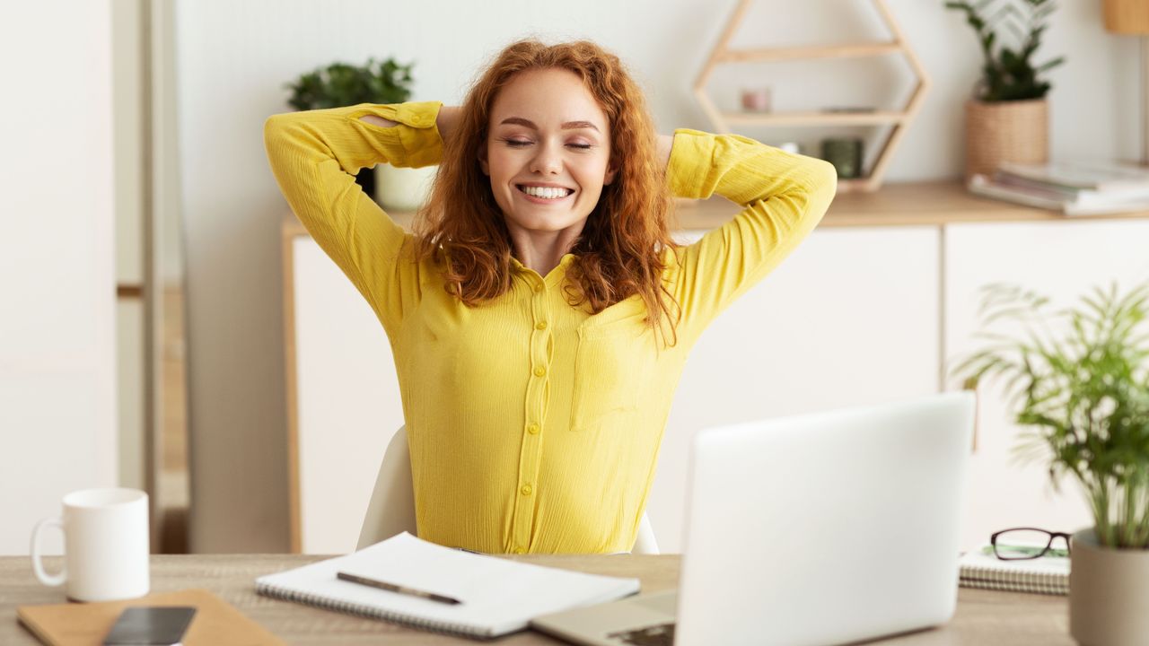 woman sitting at desk stretching 