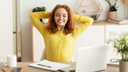 woman sitting at desk stretching 