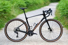 a black gravel bike standing up on its own on a gravel trail side on to the camera