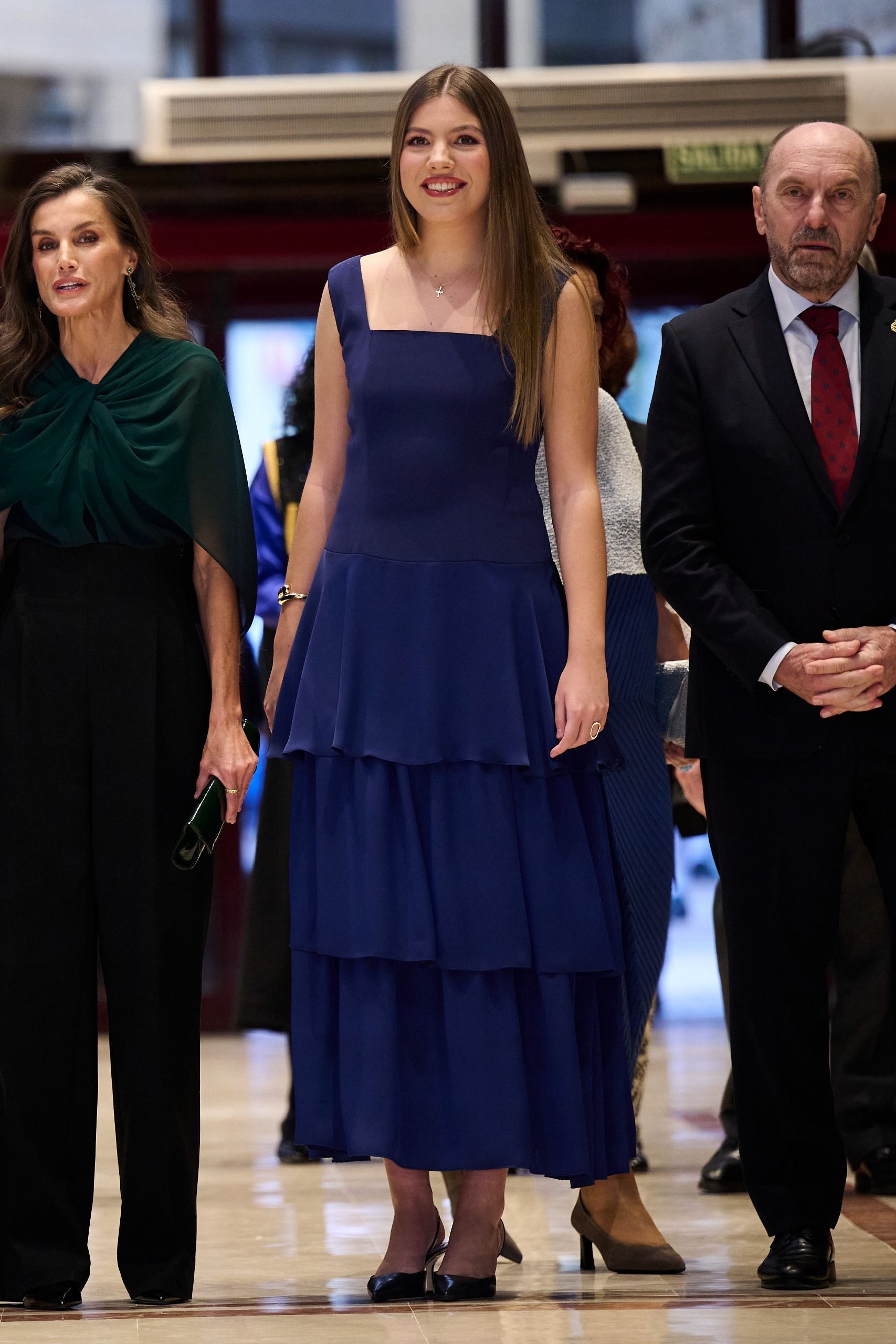 Infanta Sofia wearing a blue dress standing next to Queen Letizia