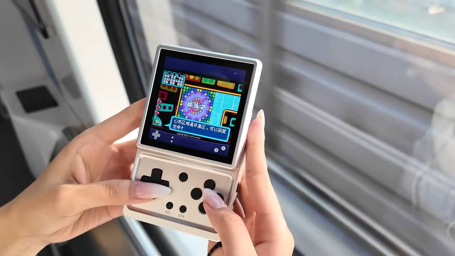 Hands with long nails using Anbernic RG Rotate to play GBA games on train.
