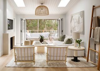 coastal living room with bifold doors leading to a balcony with glass balustrades