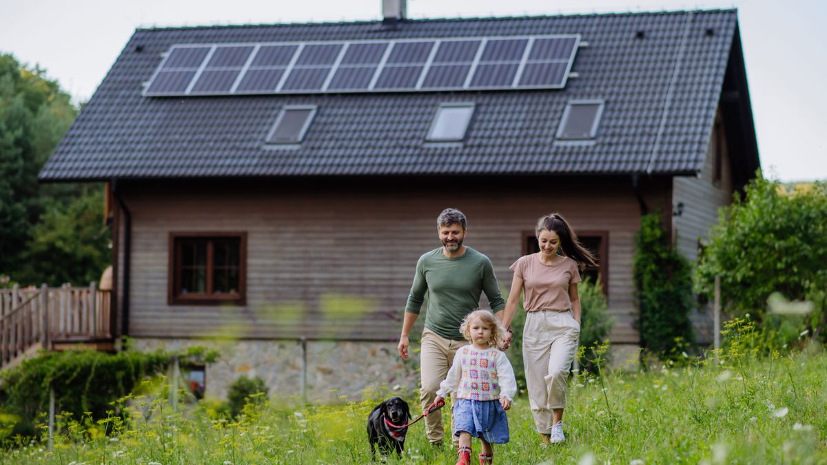 eco house with solar panels on roof and family walking a dog in the foreground