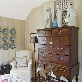 storage area with drawers and statues with cushion on armchair