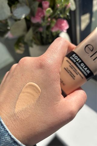 a hand holding e.l.f soft glam foundation with a smear of product