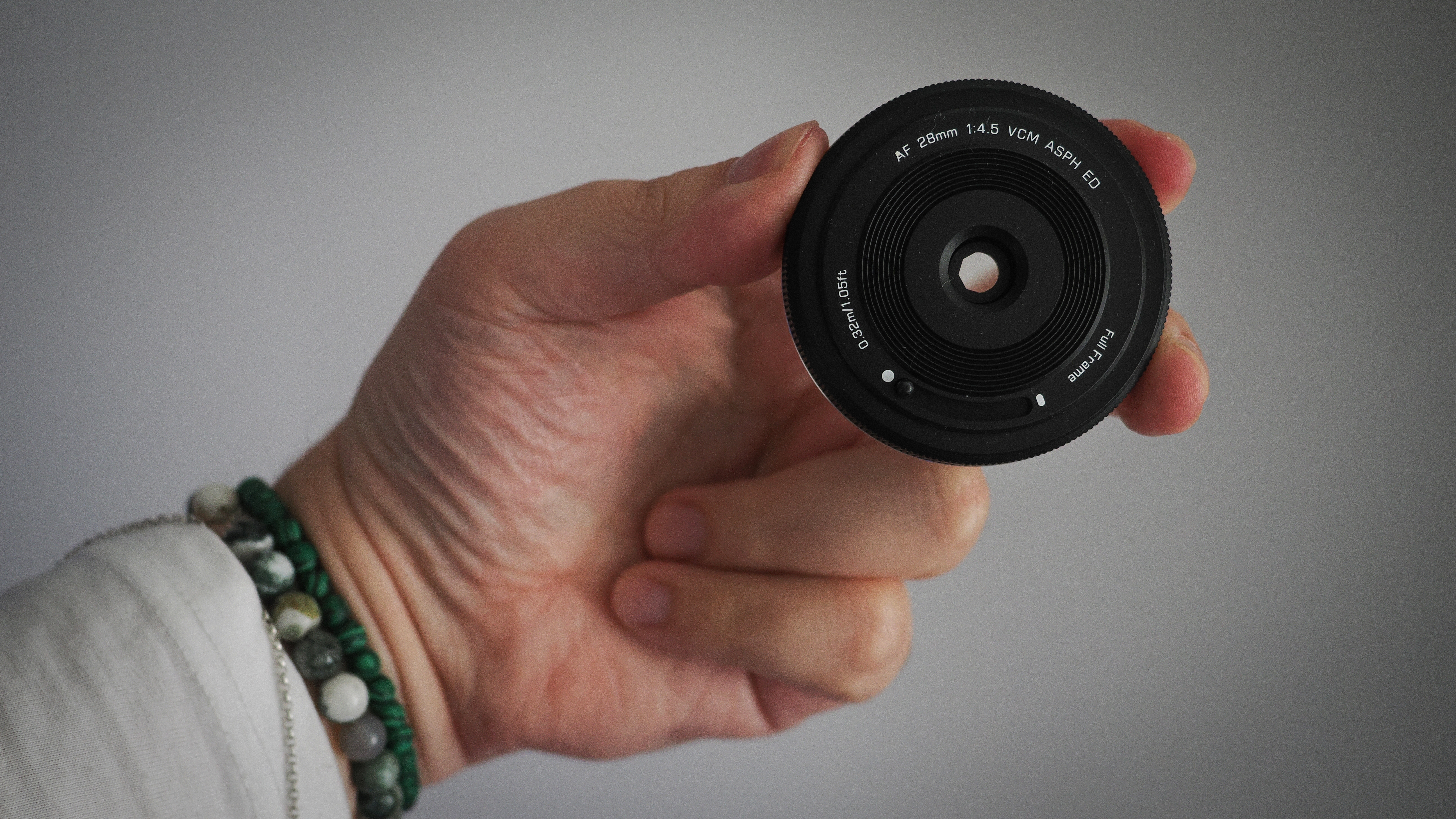 Viltrox AF 28mm f/4.5 being held in fingertips