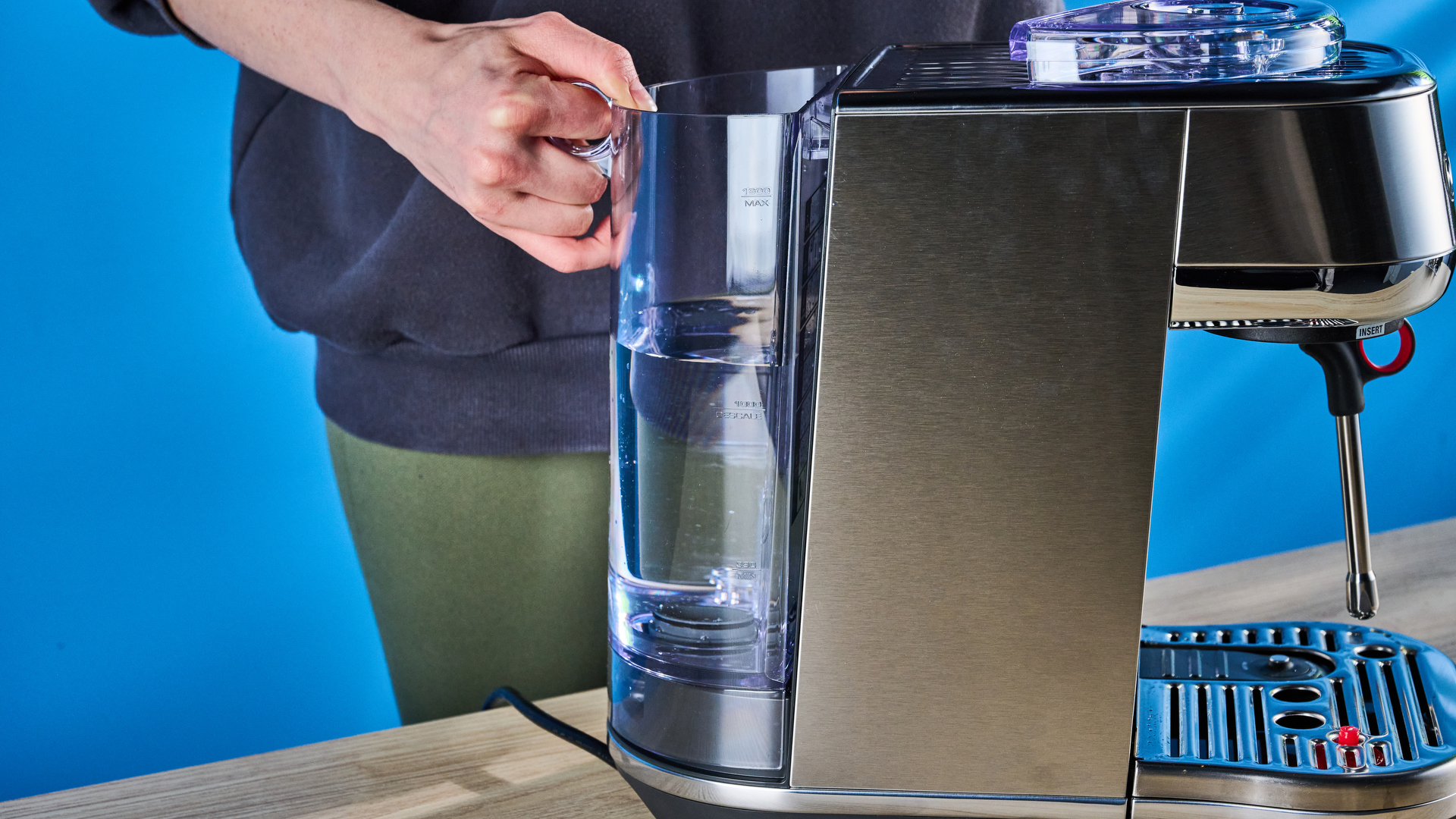 the breville bambino plus / sage bambino plus in stainless steel silver photographed against a blue background shown with its accessories including milk jug, tamper, portafilter, and shown in use extracting espresso