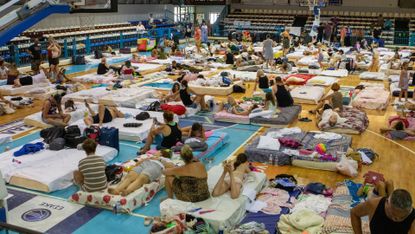 Evacuated tourists sleep on floor in temporary accommodation in Greece