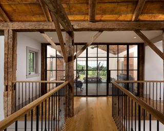 View from landing walkway with wood floor to home gym with paneled glass doors