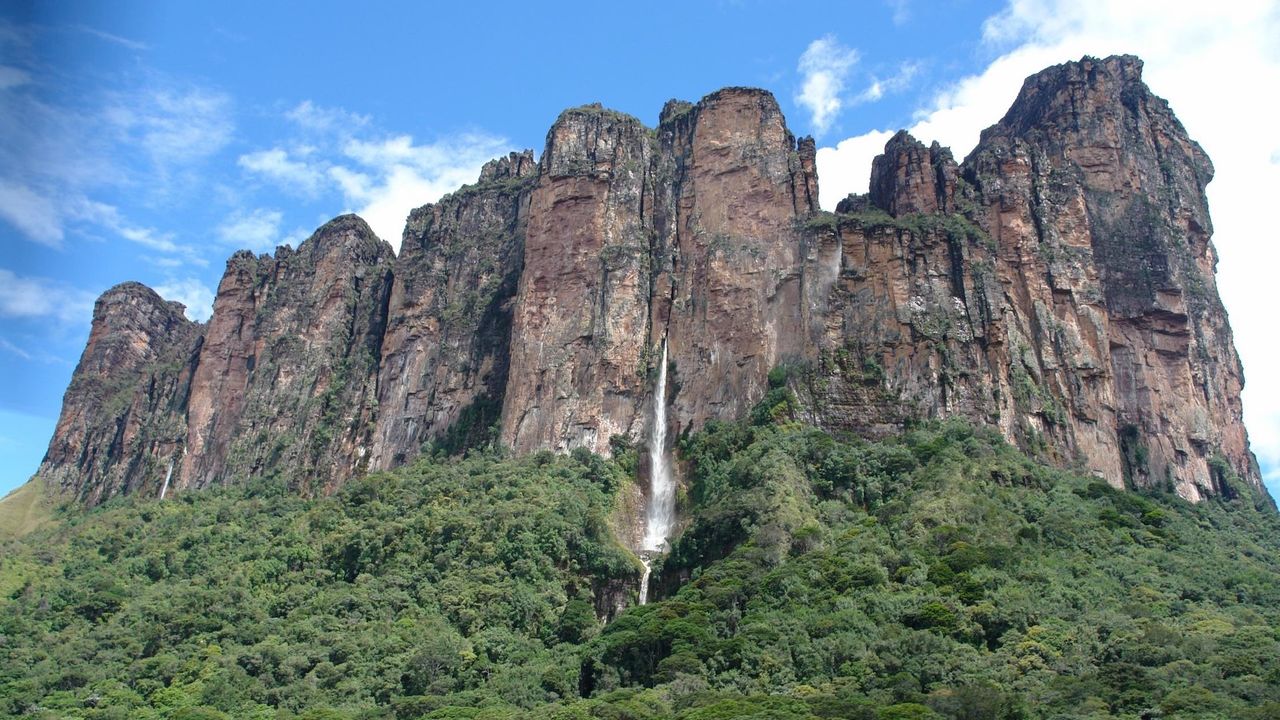 A photo of a large rock outcropping with a waterfall
