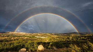 A photo of a double rainbow with a cloudy sky