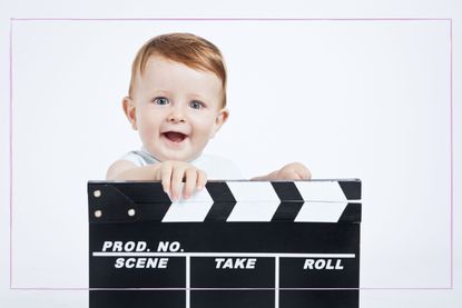 Adorable baby cine director with a film clap board over white background.