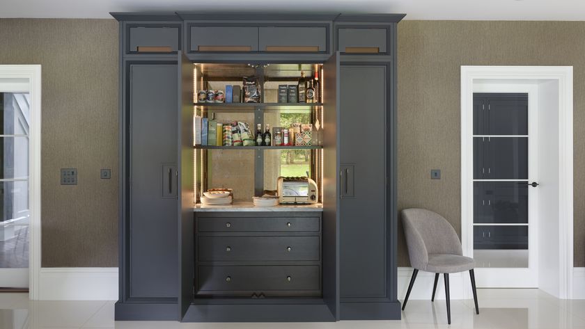large dark grey pantry cupboard with doors open and shelves and worktop inside and drawers below