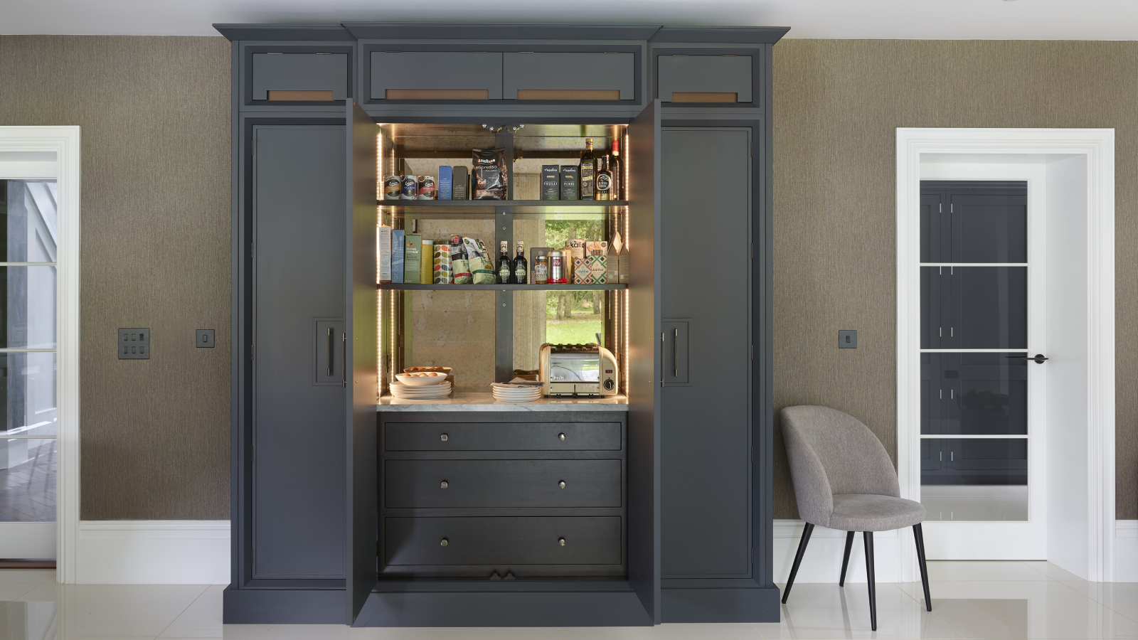 large dark grey pantry cupboard with doors open and shelves and worktop inside and drawers below