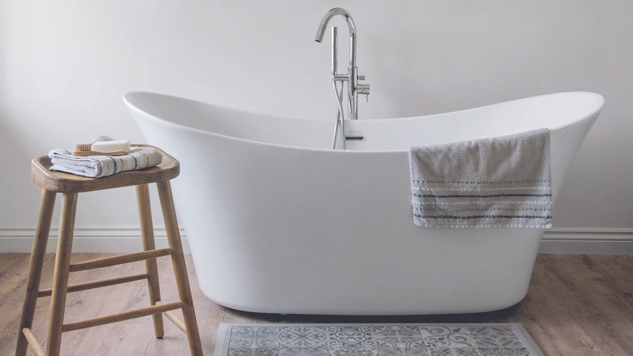 White bath in bathroom with bath mat on floor