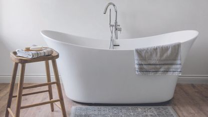 White bath in bathroom with bath mat on floor