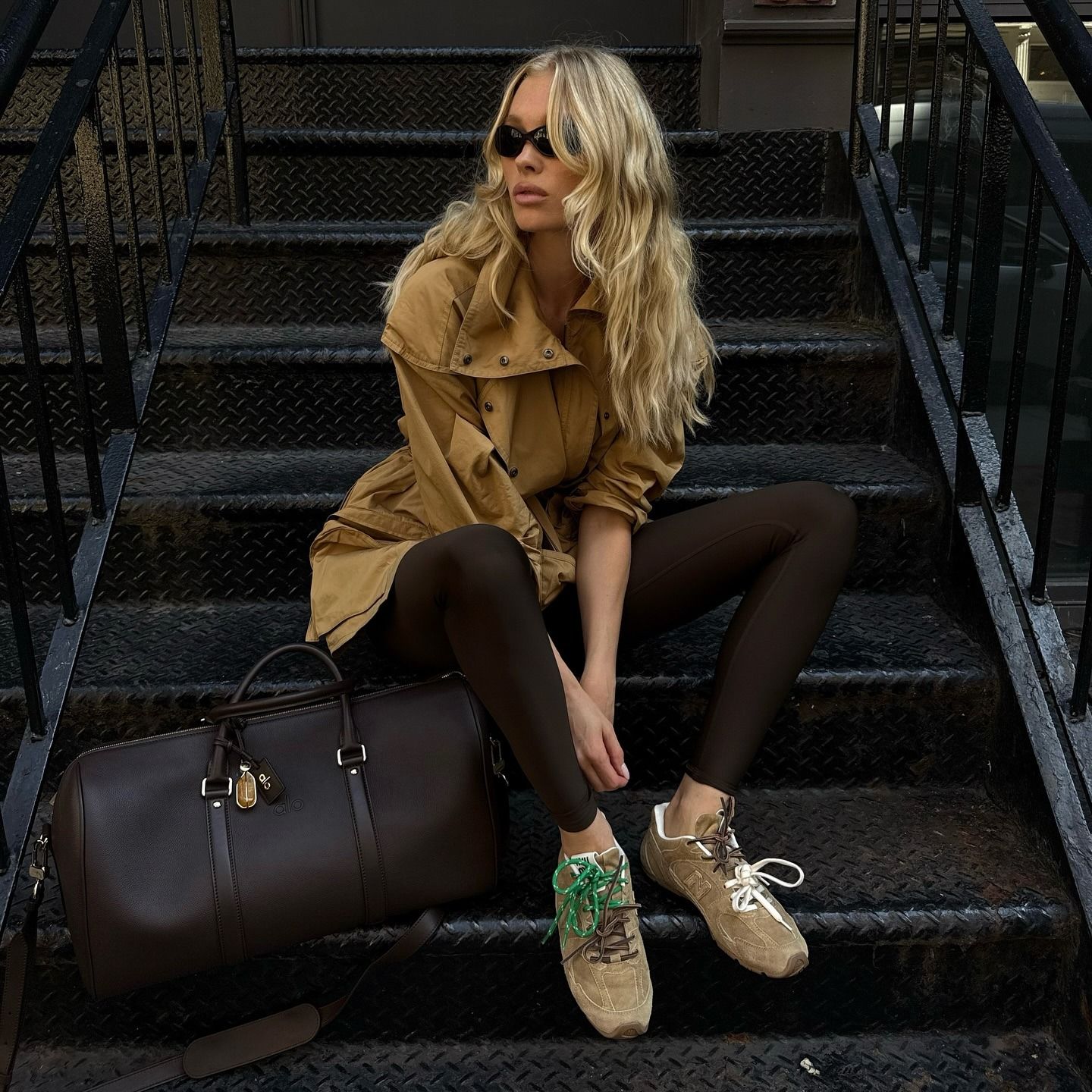 Fashion person Elsa Hosk wears a winter legging trend 2025. She wears a chocolate brown legging with Miu Miu x New Balance trainers and a cropped trench coat. This image was recently taken from her Instagram.