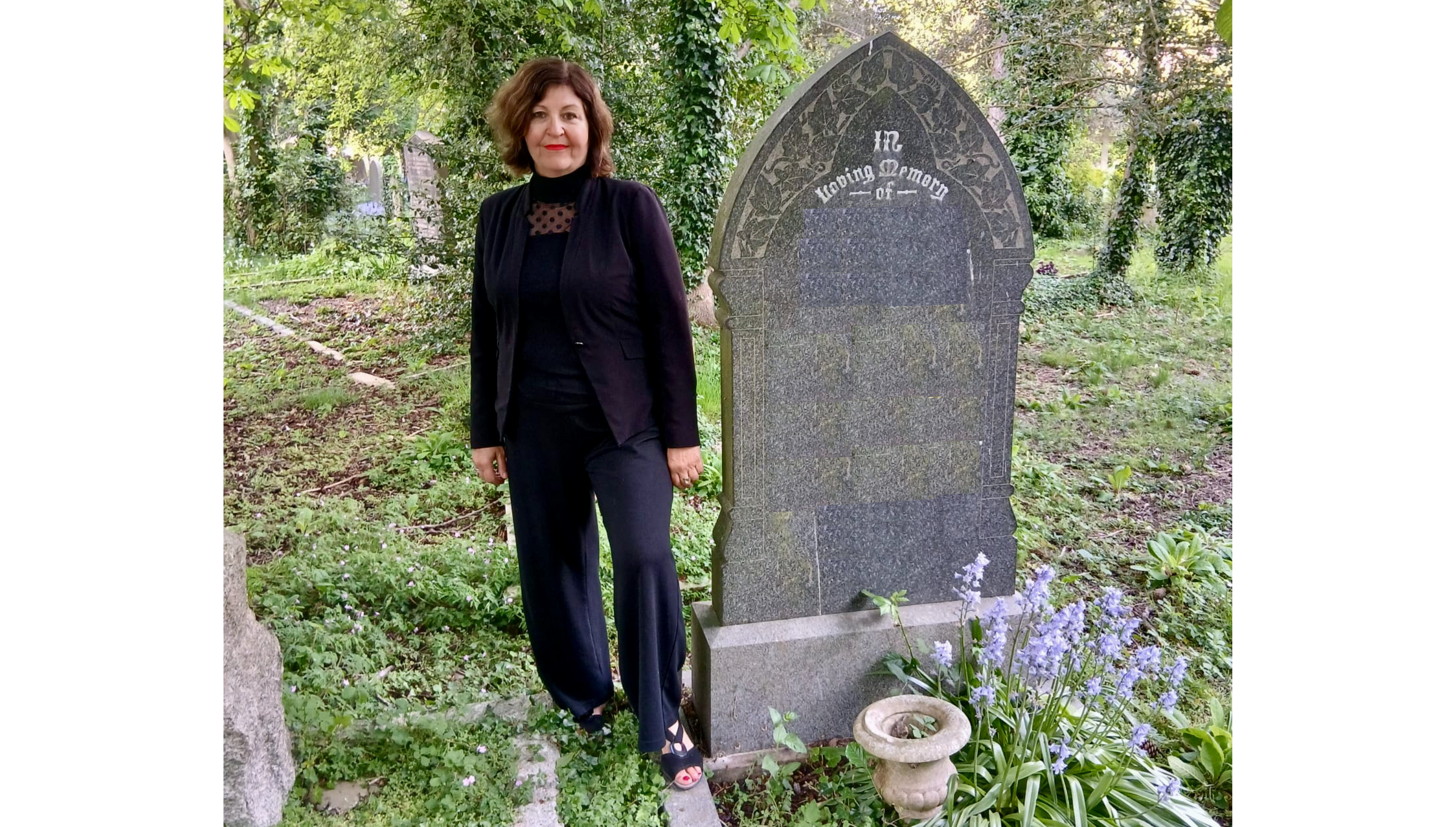 Journalist-turned-funeral celebrant Lynne Wallis in a black suit in a graveyard