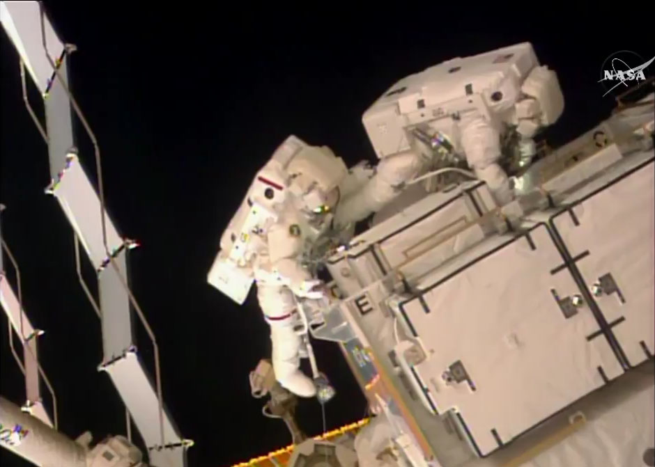 NASA astronauts Shane Kimbrough (left in red stripe) and Peggy Whitson work retrieve adapter plates outside the International Space Station during a Jan. 6, 2017 spacewalk to upgrade the orbiting laboratory&#039;s power system.