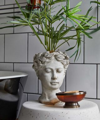 head-shaped plant pot in bathroom