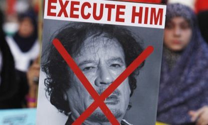A boy holds up an "Execute Gadhafi" poster during a protest earlier this year