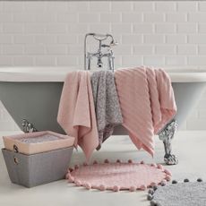 white tiled bathroom with grey bathtub and bath mat