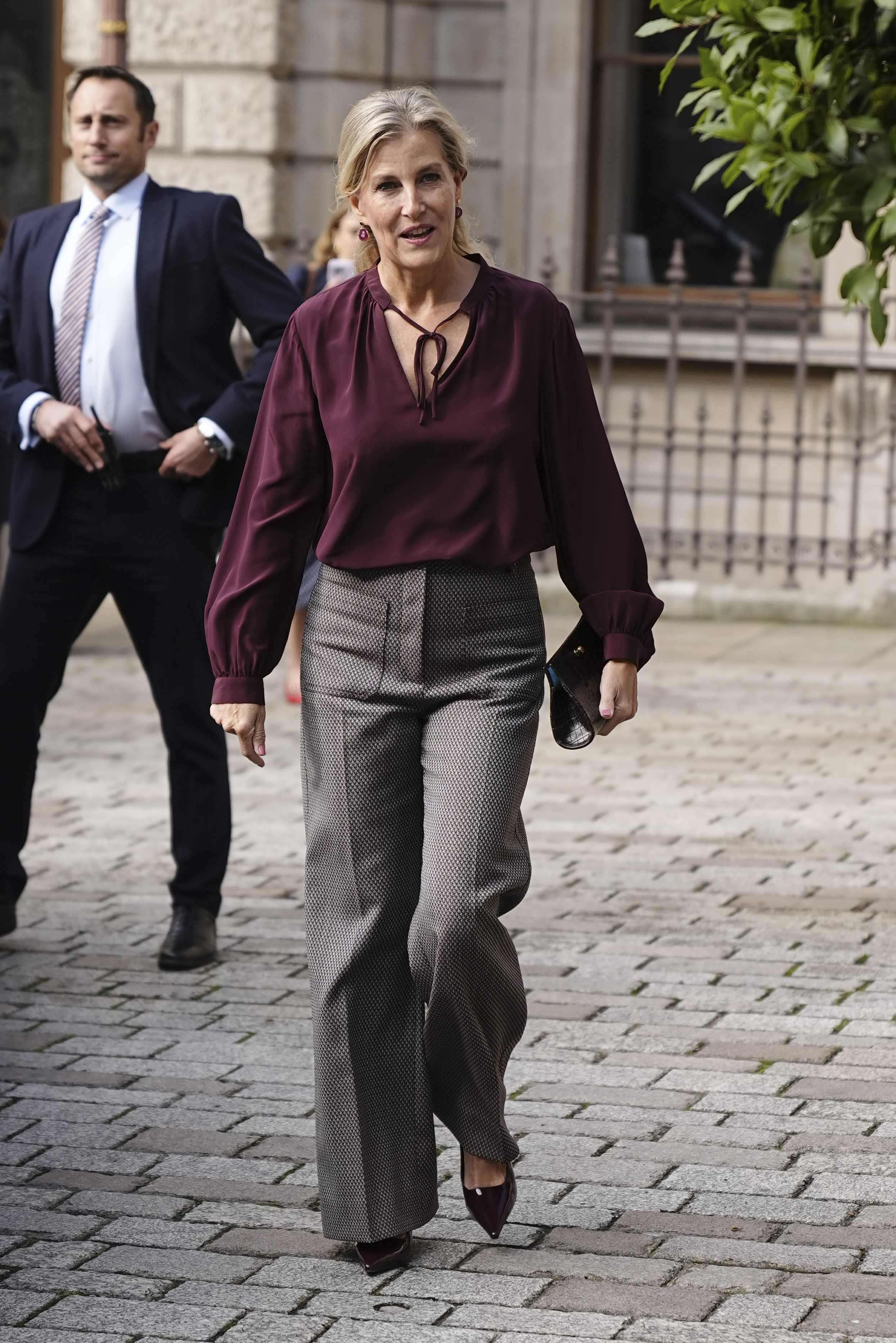Duchess Sophie in a maroon blouse and wide-legged pants walking down a sidewalk