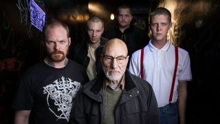Patrick Stewart standing in character as Darcy with his Nazi gang