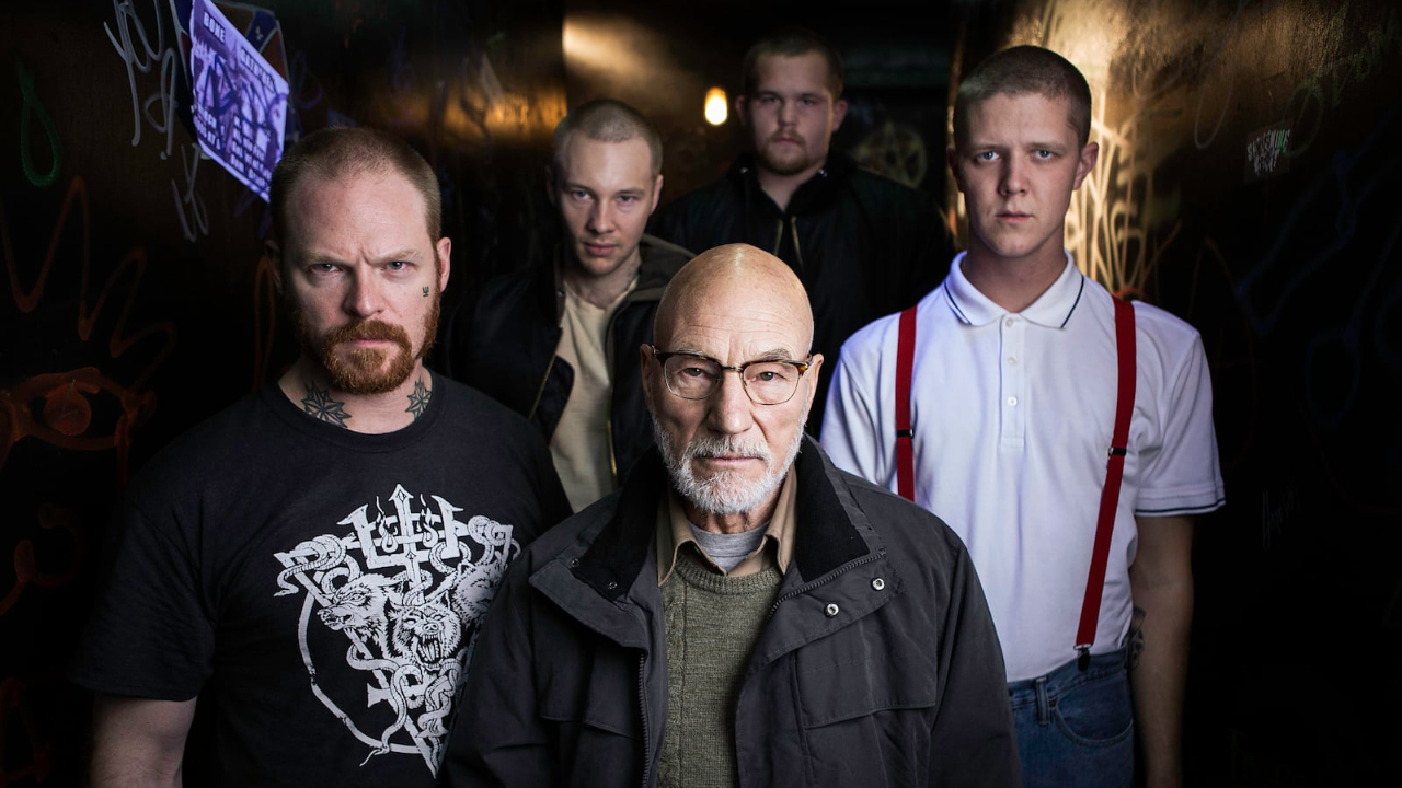 Patrick Stewart standing in character as Darcy with his Nazi gang