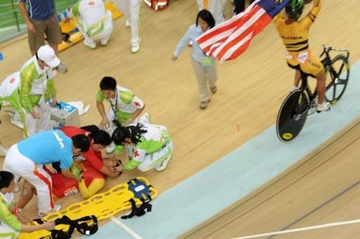 Men's keirin winner Azizulhasni Awang (Malaysia) celebrates his victory while China's Lei Zhang receives medical attention after his crash.