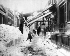 The awning of a grocery store is damaged from the weight of the snow during the blizzard of 1888 in New York, New York.