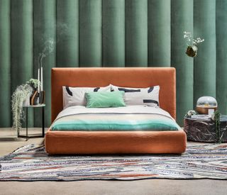 green bedroom headboard and an orange bed