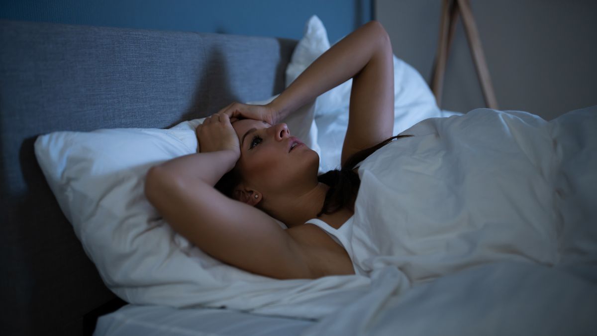 A woman lies awake in bed at night because she can&#039;t sleep and doesn&#039;t know what to do