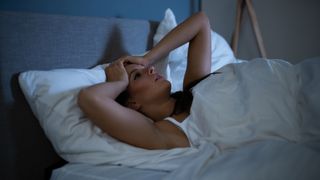 A woman lies awake in bed at night after having a nightmare during sleep