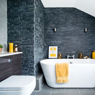 Bathroom with natural dark tiled walls and white bath tub