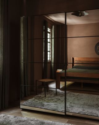 a small bedroom with mirrored wardrobes