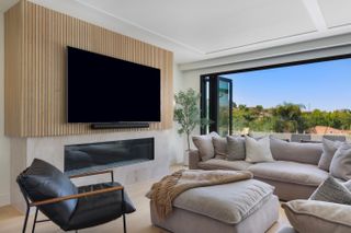 contemporary living room in soft brown tones with black leather armchair and TV