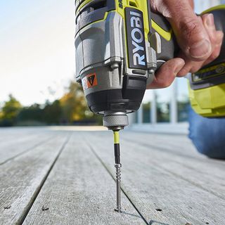 Man drilling outside decking with Ryobi drill
