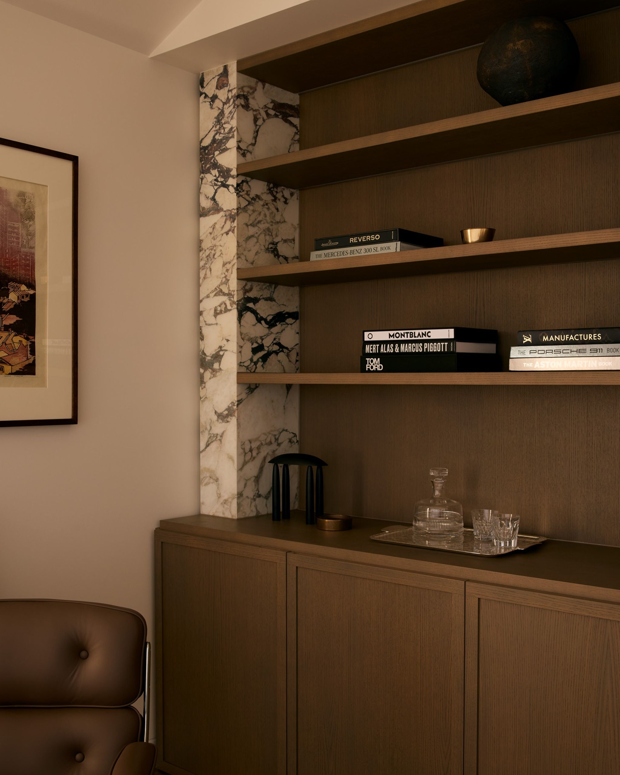 a built in cabinet made from dark wood with a plinth of marble to one side