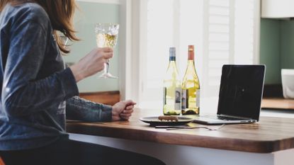 Woman drinking wine in front of a laptop